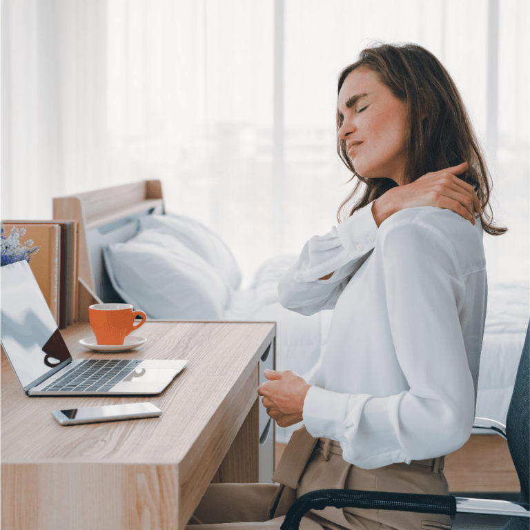 Lady sitting at a desk holding her shoulder in obvious pain